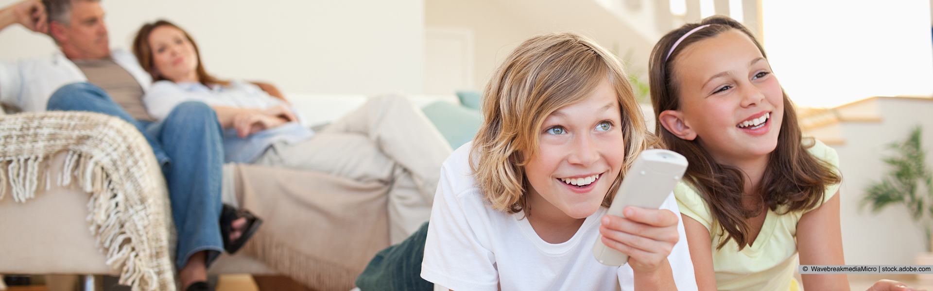 Zwei Kinder bedienen eine Fernbedienung und freuen sich
