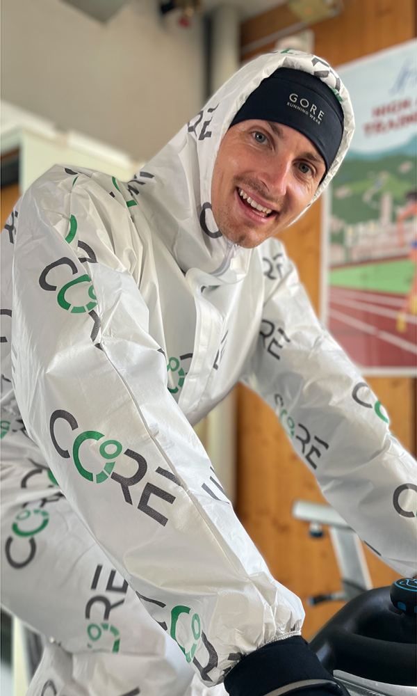 Jonathan hilbert mit vielen Kleidungsschichten und speziellem Anzug beim Hitzetraining auf dem Fahrrad