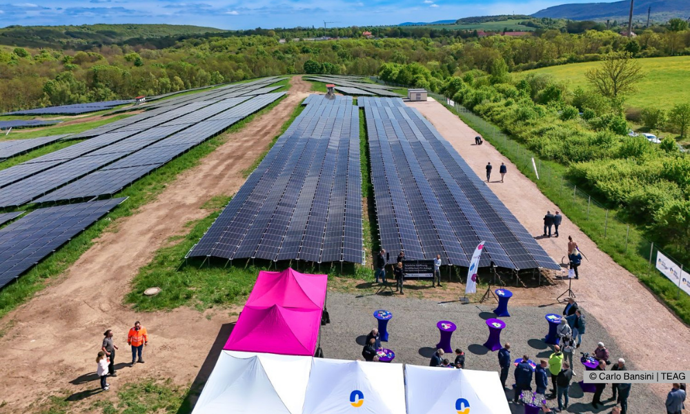 Auf der Drohnenaufnahme ist der Solarpark aus der Vogelperspektive zu sehen, ebenso wie die Stände der beiden Unternehmen TEAG und Ohra Energie. Außerdem sind die Gäste der Veranstaltung sichtbar, die sich vor Ort versammelt haben.