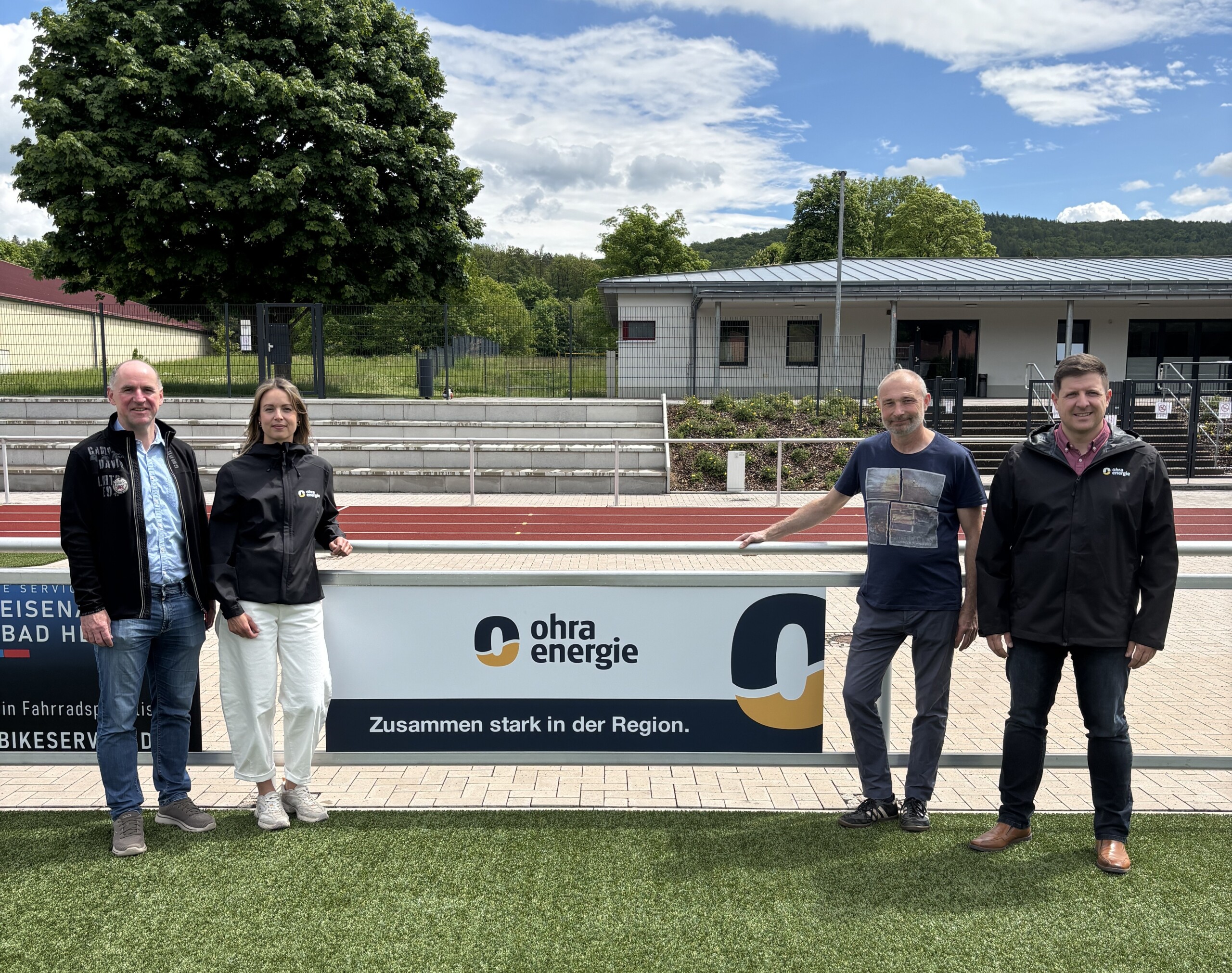 Steffen Bergemann, 2. Vorsitzender EFC Ruhla 08 e.V. (v.l.) und Sven Bartko, 1. Vorsitzender EFC Ruhla 08 e.V. (3.v.l.) bei der Übergabe der neuen Bandenwerbung von der Ohra Energie beim Sport/- und Freizeitzentrum in Thal mit Arndt Nelke, Leiter Vertrieb und Energieeinkauf der Ohra Energie (4.v.l) und Silvana Zink, Marketing der Ohra Energie (2.v.l) 