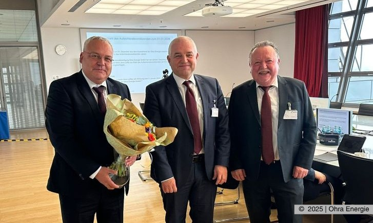    v.l. Michael Fischer (Geschäftsführer Ohra Energie GmbH), Jens Leffler (Bürgermeister Gemeinde Drei Gleichen und Vorsitzender des Aufischtsrates ab 01.01.2026), Klaus Reißig (Vorsitzender des Aufsichtsrates bis 31.12.2025) Die drei Teilnehmenden schauen lächelnd in die Kamera und dabei hält Herr Fischer einen Blumenstrauß in der Hand.