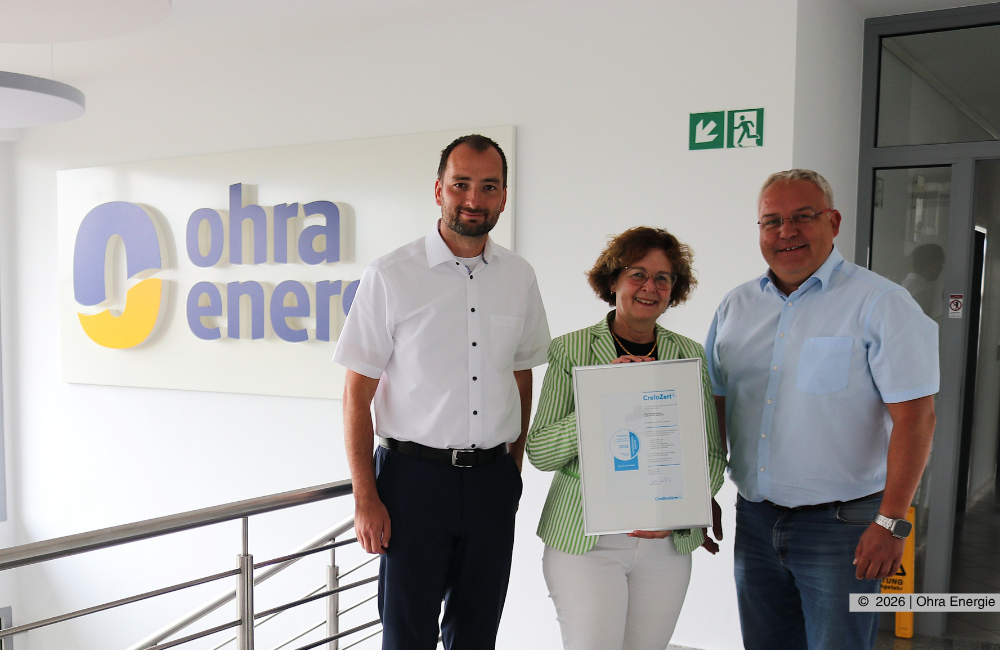 Übergabe des Zertifikats durch Viola Weichert, Prokuristin Creditreform Erfurt Hain GmbH & Co. KG an Martin Weingarten, Kaufmännischer Leiter und Prokurist der Ohra Energie GmbH (links) und Michael Fischer, Geschäftsführer der Ohra Energie GmbH (rechts). Alle Beteiligten blicken freundlich in die Kamera während sie das Zertifikat in den Händen halten.