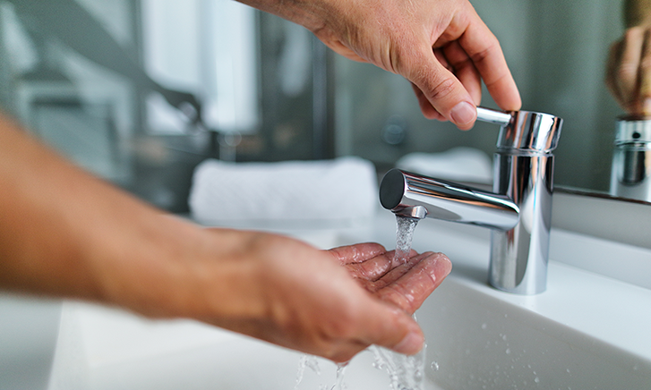 Mann schreubt Wasserhahn auf