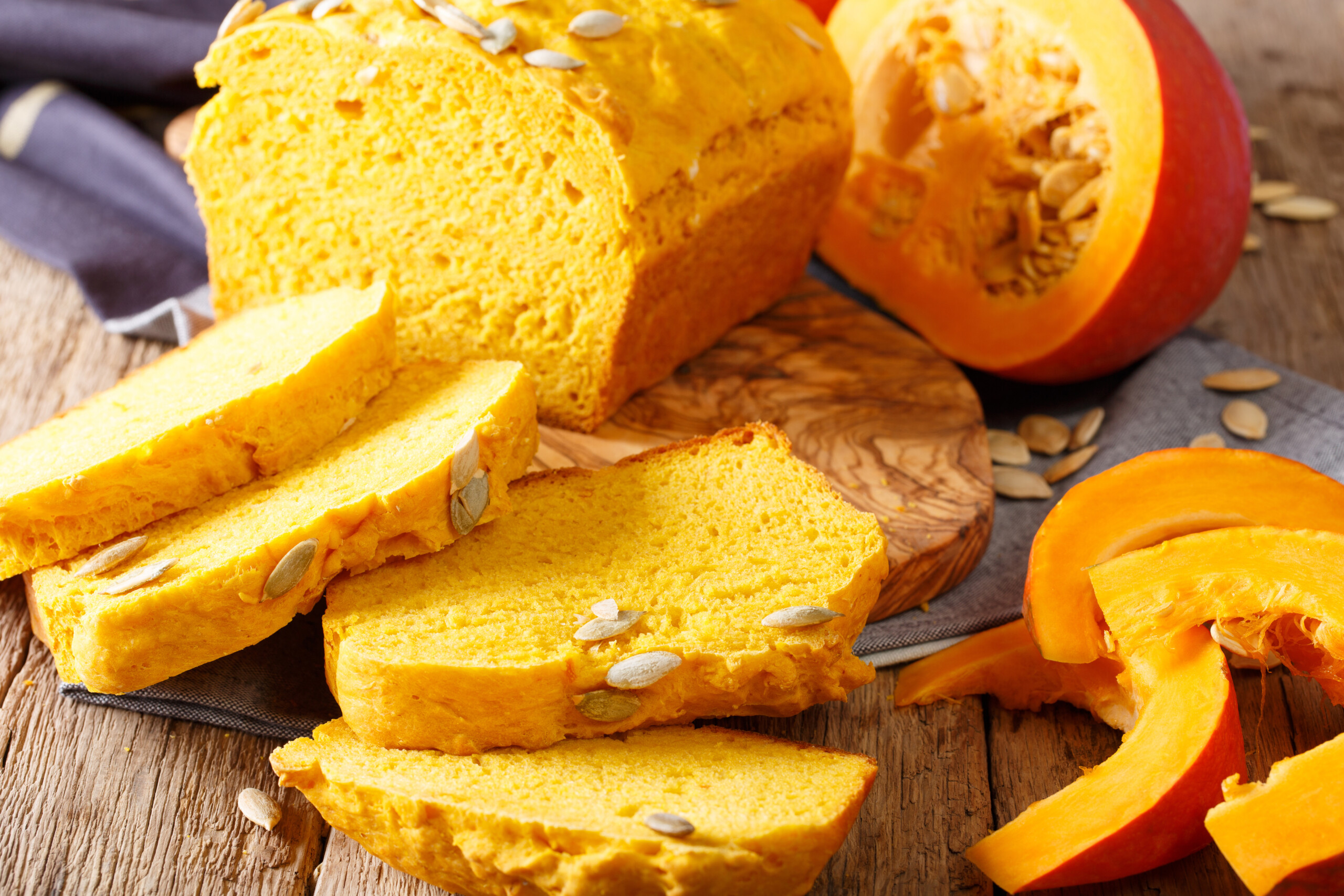 Kürbisbrot auf einem Brettchen im Hintergrund ist ein Kürbis zu sehen