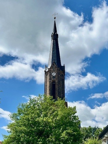 Der Turm der Sankt-Viti-Kirche in Wechmar hinter einem Baum.