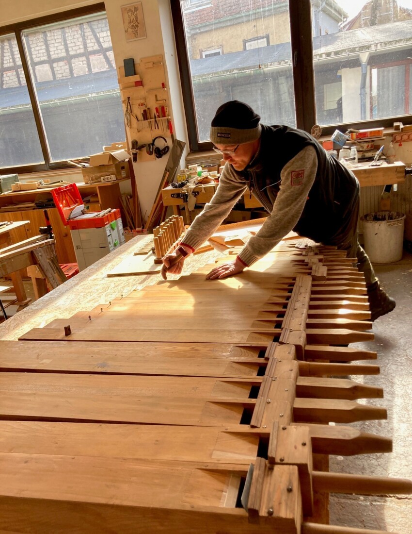 Die Orgelbaufirma Kutter aus Friedrichroda bei der Arbeit. Stehend in der Werksatt und mit dem Finger auf einzelne Holzteile zeigend.